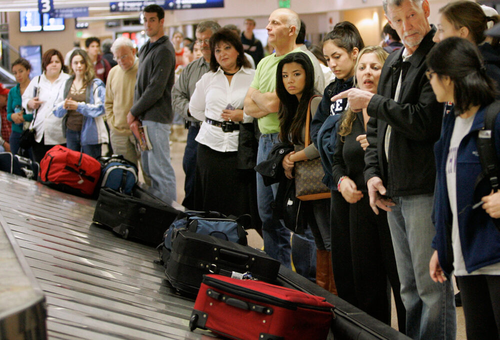 ** FILE ** In this Nov. 21, 2007 file photo, travelers line up to get their luggage in the Southwest Airlines baggage claim at the San Jose International airport in San Jose, Calif. It's time to think of the inside of your carry-on suitcase as real estate: Make the most of what you've got, keep it functional and make neatness count. The carry-on bag could be the solution to some of the summer travel season's likely woes, including checked baggage fees on American Airlines and possibly other carriers, but it also has the potential to cause headaches. (AP Photo/Marcio Jose Sanchez, file)